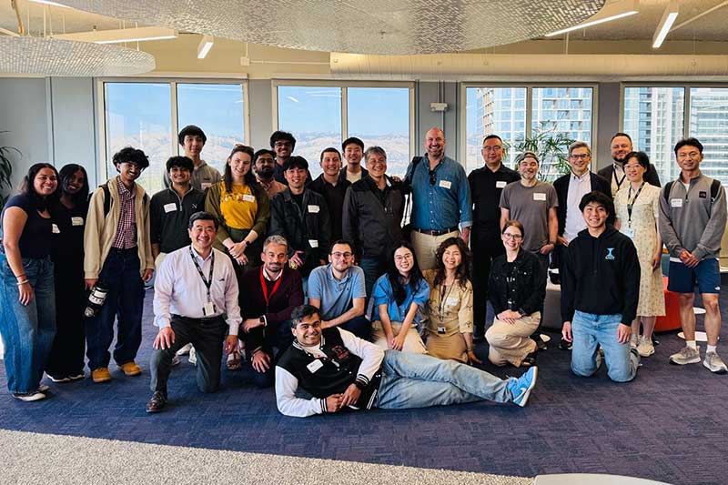 27 Silicon Valley faculty and students stand, kneel, and lay on the floor while posing for a photo