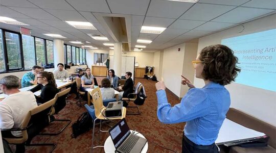 Lucy Havens gestures while speaking to a room of researchers