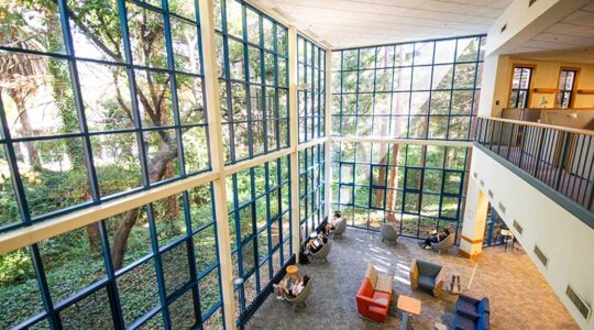 Students study in a large atrium at Northeastern Oakland's library